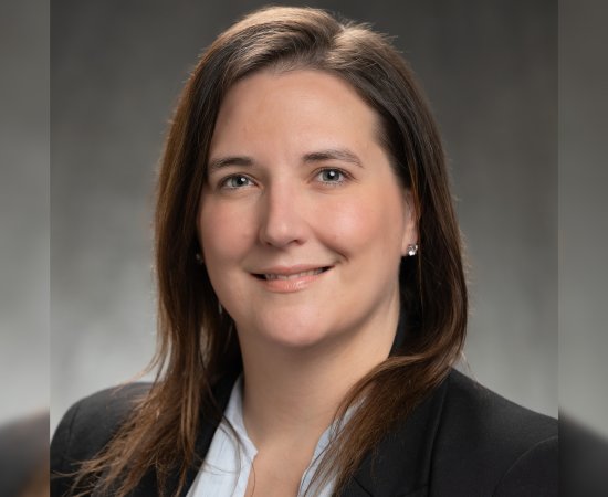 Jennifer Waters, woman with brown hair down past shoulders, in a black blazer, smiles at camera.