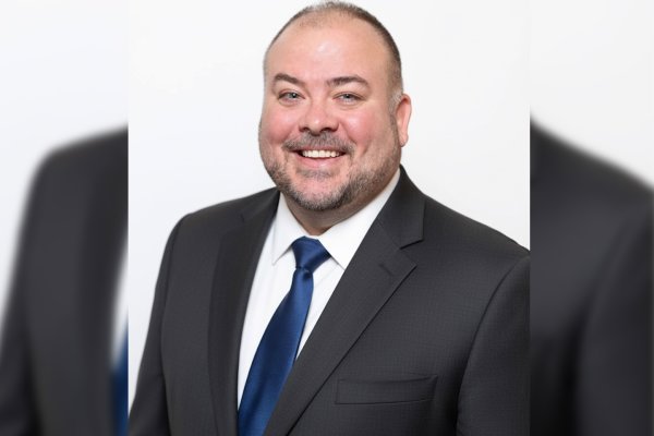 Harol Coleman in dark suit, white shirt. and blue tie.