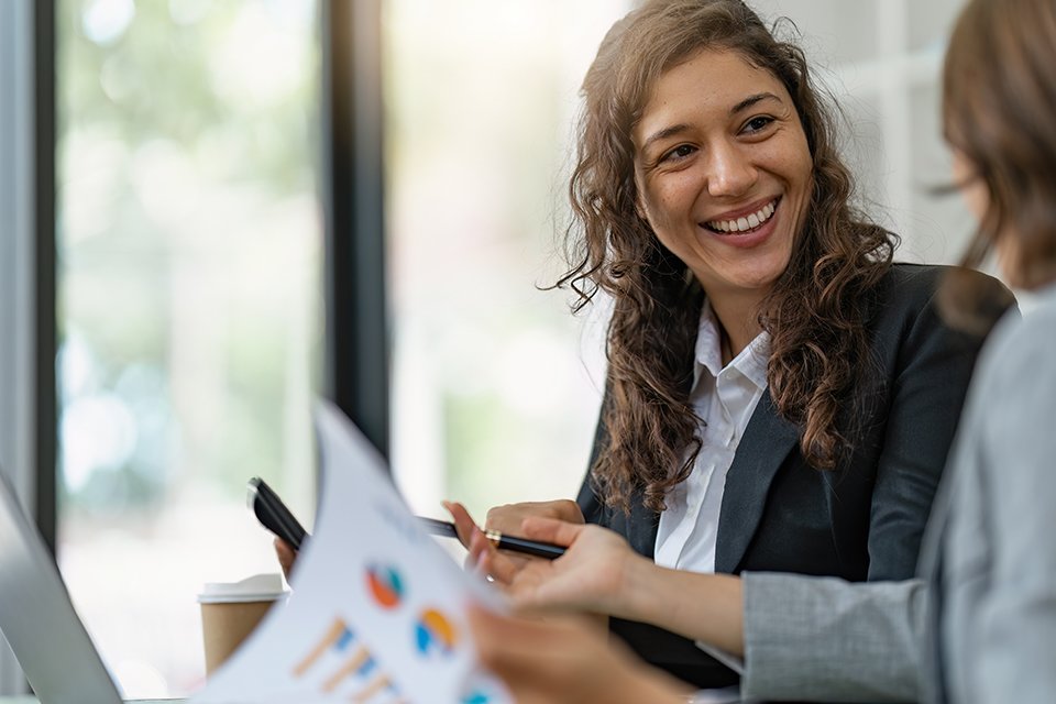 Female accountant smiles at colleague in a business setting.